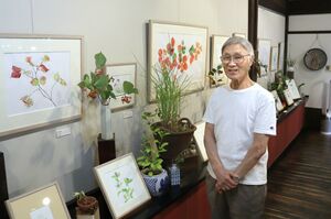 作品と花と一緒に笑顔を見せる外山康雄さん=2022年9月、南魚沼市万条新田のギャラリー「野の花館」