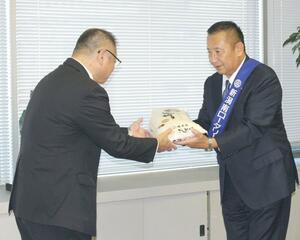 井崎規之副市長(左)にコシヒカリを手渡す新潟南ロータリークラブの加藤祐介会長=新潟市役所