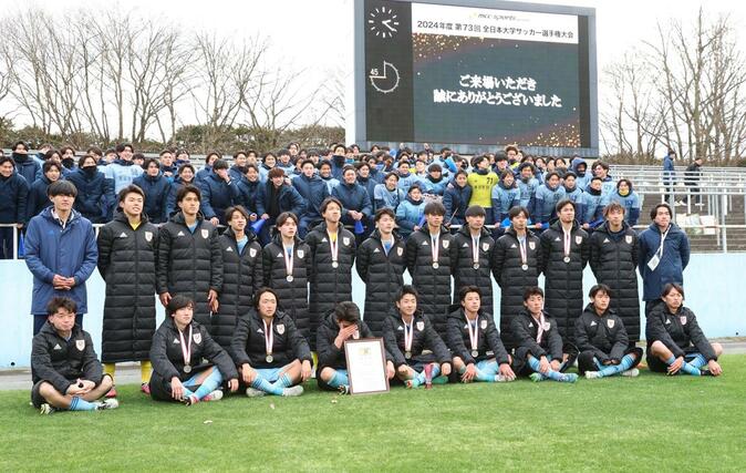 初優勝を逃し、悔しい表情でスタンドの応援団と記念撮影する新潟医療福祉大選手＝栃木県グリーンスタジアム