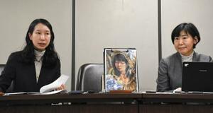 記者会見する原告側の代理人弁護士。中央の絵は原告の自画像=20日午後、東京・霞が関の司法記者クラブ