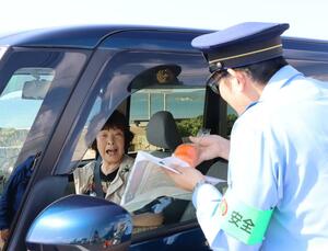ドライバーに柿を配り、施錠を呼びかけた啓発活動=佐渡市河原田本町
