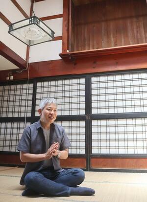 作品制作などのために購入した古民家で展望を語る伴野智さん=佐渡市両津湊