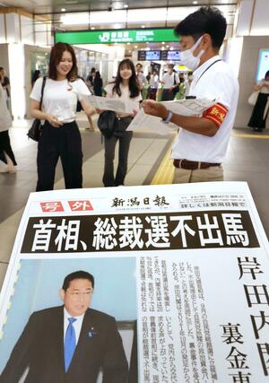 岸田文雄首相の自民党総裁選不出馬を報じる本紙号外を手にする人々=8月14日、新潟市中央区のJR新潟駅