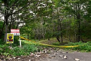 林道の入り口に張られた規制線とクマ出没に注意を呼びかける看板(左端)=5日午前、宮城県栗原市