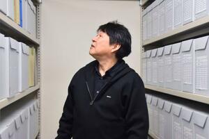 「薬害研究資料館」の活動拠点で保管する資料を眺める理事長の花井十伍さん=7日、京都市