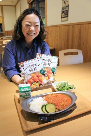 「トマ味噌カレー豚丼」のレトルト商品を手にする、道の駅SORAIRO国上の林美樹駅長。手前は食堂で提供しているメニュー=燕市国上