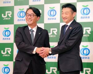 記者会見で握手するJR東日本の喜勢陽一社長(左)と西武鉄道の小川周一郎社長=19日午後、東京都内