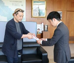 売上金を寄付し、目録を手渡すNANOBRANDの高橋憲示代表社員CEO(左)=三条市役所