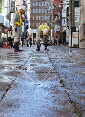 消雪パイプのノズルに詰まった砂や小石を取り除く点検作業=長岡市坂之上町1