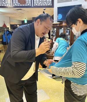 　引退相撲のボランティアスタッフにサインする大山親方＝４日、東京都内