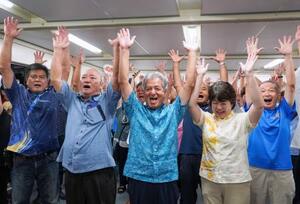 沖縄県与那国町長選で初当選を決め、万歳する上地常夫氏(中央)=24日夜、与那国町