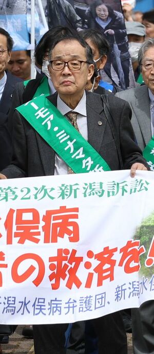 新潟水俣病の訴訟で原告らと横断幕を持って新潟地裁に入廷する中村洋二郎さん=2024年4月、新潟市中央区