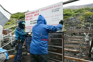 富士山の登山道を冬季閉鎖するため、看板を設置する作業員=10日午後、静岡県富士宮市