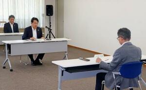 毎年50億円前後を拠出する新たな仕組みについて、福井県の中村保博副知事(右)に報告する関電の水田仁原子力事業本部長(中央)=25日午後、福井県庁