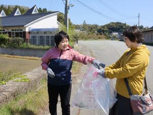 道路沿いのごみを拾う河野愛実さん(左)と母の恵さん(右)=佐渡市小木町