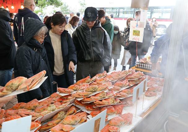 店頭に並んだカニを品定めする買い物客=12月30日、長岡市寺泊下荒町の「市場通り 金八」