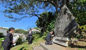 　「戦没新聞人の碑」に献花し、手を合わせる報道関係者＝３０日午前、那覇市