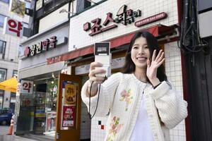 　韓国・ソウルの街中でユーチューブの撮影をするカン・ナラ。小型のデジタルカメラはいつも持ち歩いている＝２０２６年４月（撮影・橋爪優典、共同）