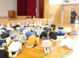 弾道ミサイルの飛来を想定した訓練で身を守る姿勢を取る新井中央小の児童たち=妙高市諏訪町2