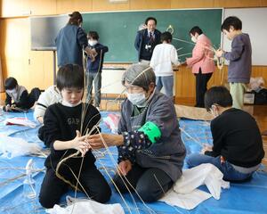 稲わらをねじったり、飾り付けたりして思い思いのリースを作る児童ら=1月21日、佐渡市羽茂本郷