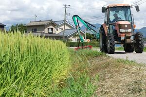 草刈り機を搭載し、雑草を刈り取るトラクター=村上市(写真映像部・佐藤将志)