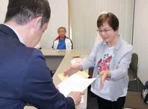 要望書を市の担当者に渡す魚沼市民温水プールを造る会の山田たつ子代表(右)=魚沼市役所