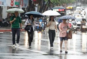 台風18号の影響で雨が降る中、歩く人たち=23日、台北(AP=共同)