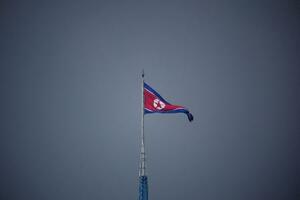 南北軍事境界線の北側にある北朝鮮の「宣伝村」に掲げられた国旗。韓国側から撮影された=2022年7月(ロイター=共同)