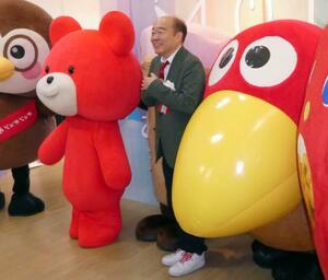 　「お菓子ミュージアム天保山」で、「キョロちゃん」（右）らと記念撮影する吉寿屋の神吉一寿社長＝１９日午前、大阪市港区