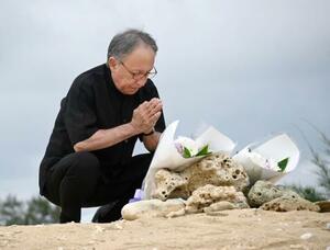 　沖縄県名護市辺野古沖での転覆事故の現場を臨む「瀬嵩の浜」で手を合わせる玉城デニー知事＝２１日午後