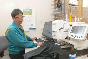 ミシンを使って学生服にネームの刺しゅうをする石原政人さん＝柏崎市西山町和田