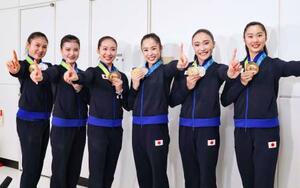 　帰国した成田空港でポーズをとる新体操の世界選手権で団体総合初の金メダルを獲得した鈴木歩佳（中央右）ら日本代表＝２６日