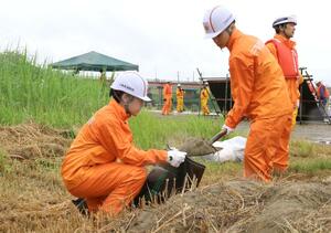 土のうを作って積む訓練をする三条市の学生消防隊=6月23日、三条市上須頃