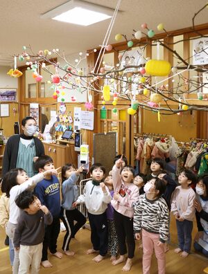 完成した団子木を見上げるひだまりこども園の子どもたち=胎内市十二天
