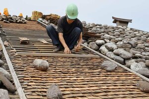 渡邉邸の石置き木羽葺き屋根の木羽板を取り換える職人=関川村下関