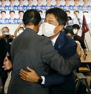 初当選が決まり、高鳥修一・自民党県連会長と抱き合う、小林一大さん=7月10日、新潟市中央区