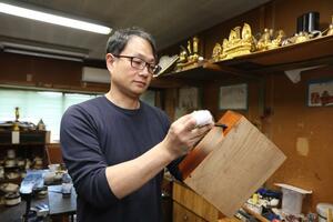 下地塗りの最初の工程の「木地固め」をする笠井俊裕さん。「きれいな仕上がりのためには下地が大切だ」と話す=新潟市南区能登2