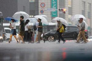 強い雨が降る中、傘を差して歩く人たち=10日午後、福岡市
