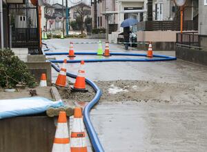地震で被害が出た下水管の応急措置として道路上に渡された仮設ホース=18日、新潟市西区鳥原