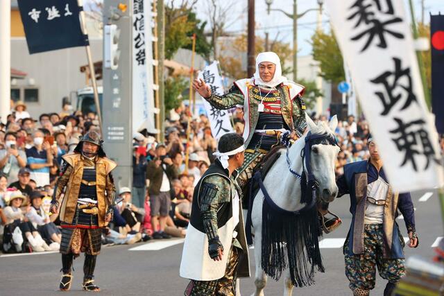 １００回目の謙信公祭で上杉謙信役を務め、沿道の観客に笑顔で手を振る松平健さん＝２３日、上越市