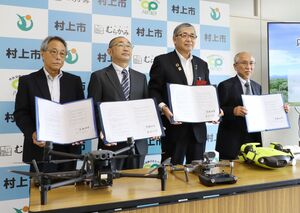 ドローンを活用した災害時の応援協定の締結式に臨んだ高橋邦芳市長(右から2人目)と3社の代表ら=村上市役所