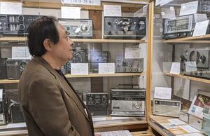 日本ラジオ博物館に展示されたラジオを眺める岡部匡伸館長=5月3日、長野県松本市(日本ラジオ博物館提供)