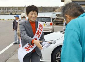 佐渡市の姫津漁港に集まった有権者に握手を求める西村智奈美=10月24日