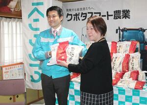 新潟県フードバンク連絡協議会の山下浩子会長にコメを手渡す新潟クボタの吉田丈夫社長(左)=三条市北新保1