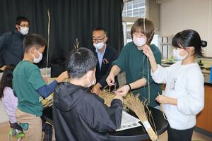 協力してわらぼうきを作る刈羽小の５年生と保護者＝刈羽村割町新田