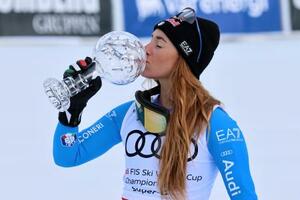 アルペンスキーW杯、女子スーパー大回転で種目別優勝を決め、トロフィーにキスするソフィア・ゴッジャ=22日、リレハンメル(AP=共同)