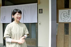 のれんを掛けた「助産院まんまる」の入り口に立つ藤橋杏美さん=上越市柿崎区