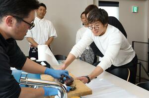 魚のさばき方教室を手伝う木村勝一さん(右)。「寺泊で自由に活動ができるのは、父や祖父が漁師として知られていたから」と話す=3月上旬、長岡市寺泊上田町