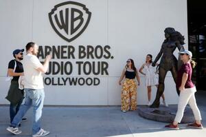 　「ワーナー・ブラザース・スタジオ」にあるワンダーウーマンの銅像と写真を撮る観光客＝２月、米カリフォルニア州（ゲッティ＝共同）