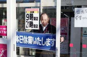 　クマの侵入を受け、休業のお知らせを張る「イオン能代店」の関係者＝１６日午後２時５８分、秋田県能代市